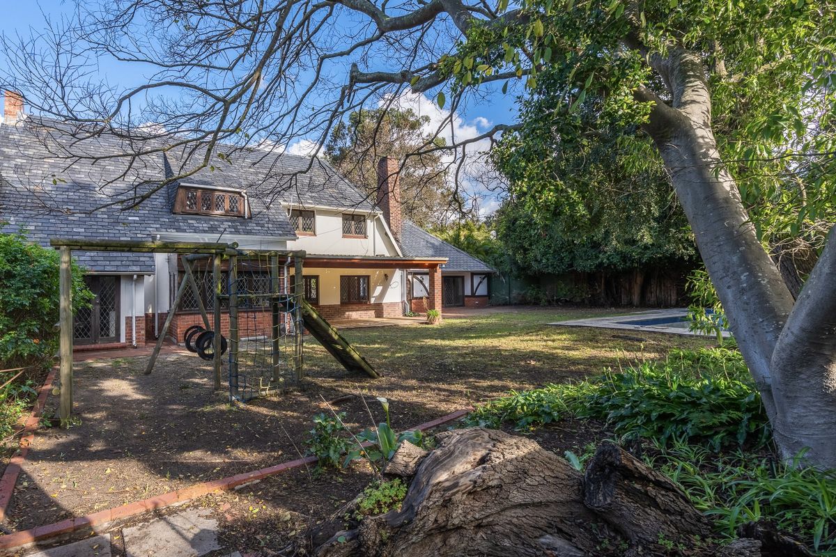 Rear view of the property featuring a slate roof, covered patio, swimming pool, and established garden area.