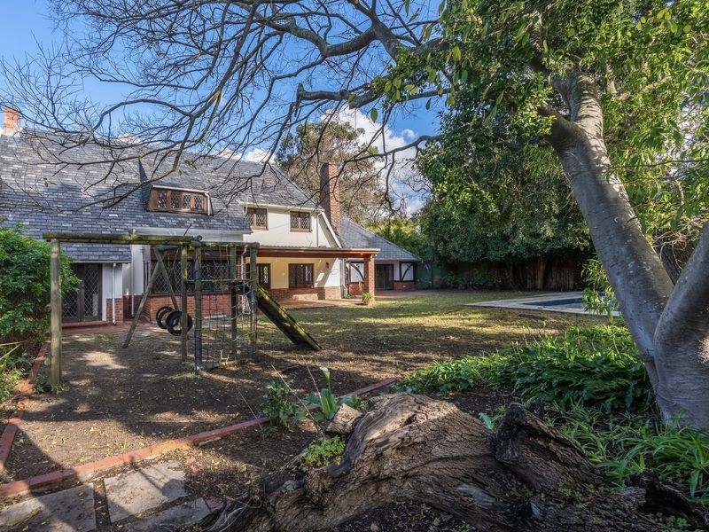 Rear view of the property featuring a slate roof, covered patio, swimming pool, and established garden area.