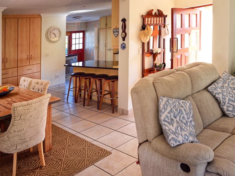 Open plan living and dining area featuring tiled flooring, a kitchen island with granite countertops, and built-in cabinetry.