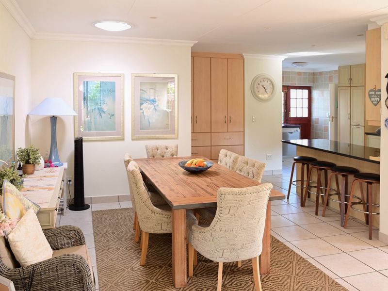 An open-plan dining and kitchen area featuring tiled flooring, built-in cabinetry, a kitchen island with breakfast bar seating, and natural light from a skylight.