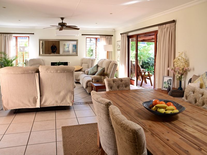 Spacious open-plan living and dining area featuring tiled floors, a ceiling fan, air conditioning, and direct access to the outdoor patio through sliding doors.