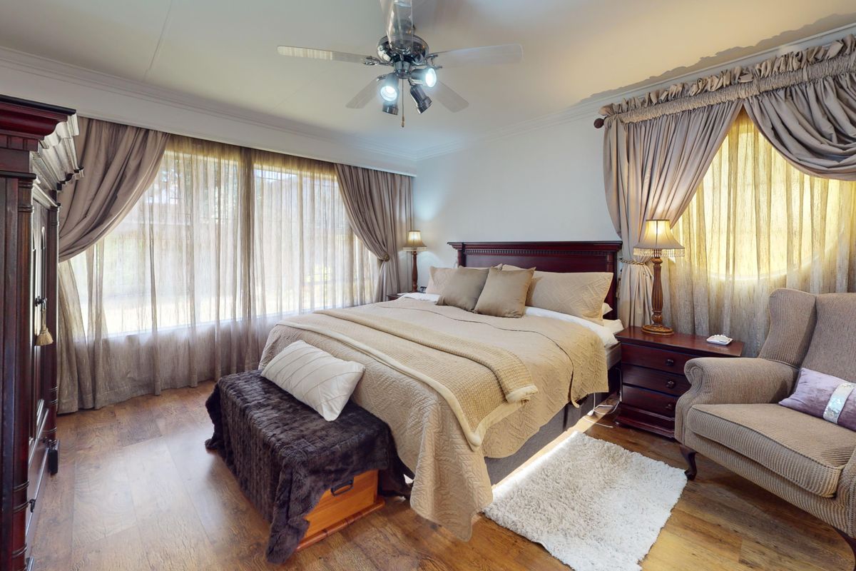 A well-maintained bedroom featuring laminate flooring, crown molding, and a ceiling fan, offering a comfortable and classic living space.
