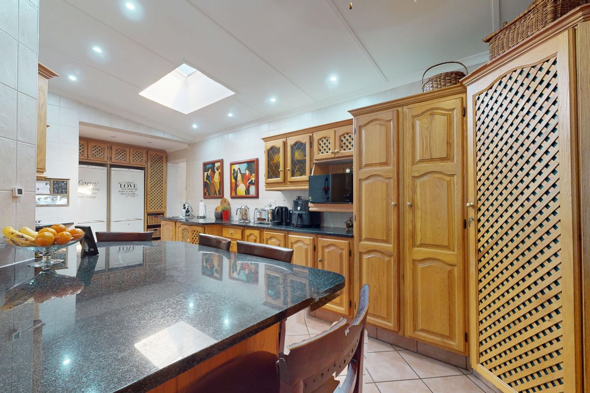 Spacious kitchen featuring extensive wooden cabinetry, granite countertops, a central island, and a skylight providing natural light.