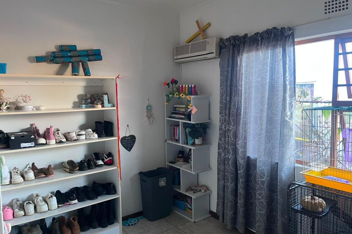 A bedroom featuring tiled flooring, a wall-mounted air conditioning unit, and a window with curtain treatments.