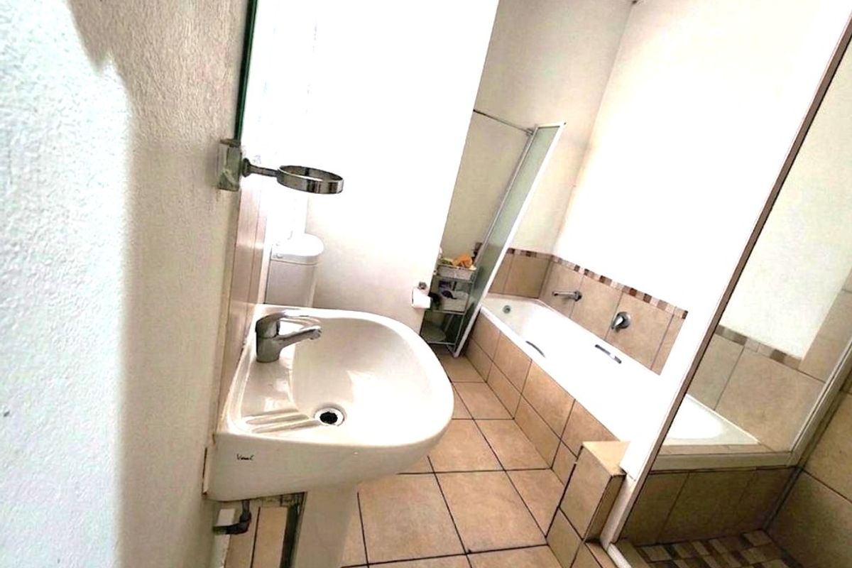 A functional bathroom featuring a pedestal basin, bathtub, and separate shower enclosure with tiled finishes throughout.