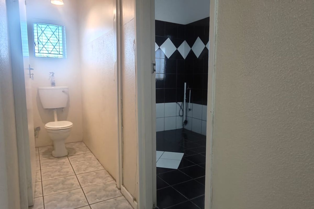 A functional bathroom featuring a toilet and contrasting black and white wall tiling, presenting an opportunity for modern renovation and aesthetic updates.