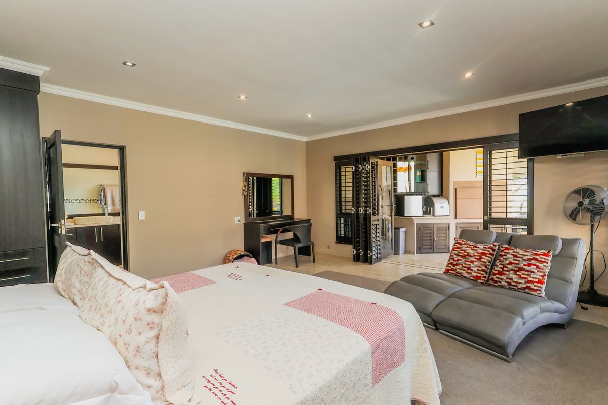 Spacious bedroom featuring recessed lighting, built-in cabinetry, and bi-fold doors opening to an adjacent area, with an integrated en-suite bathroom.