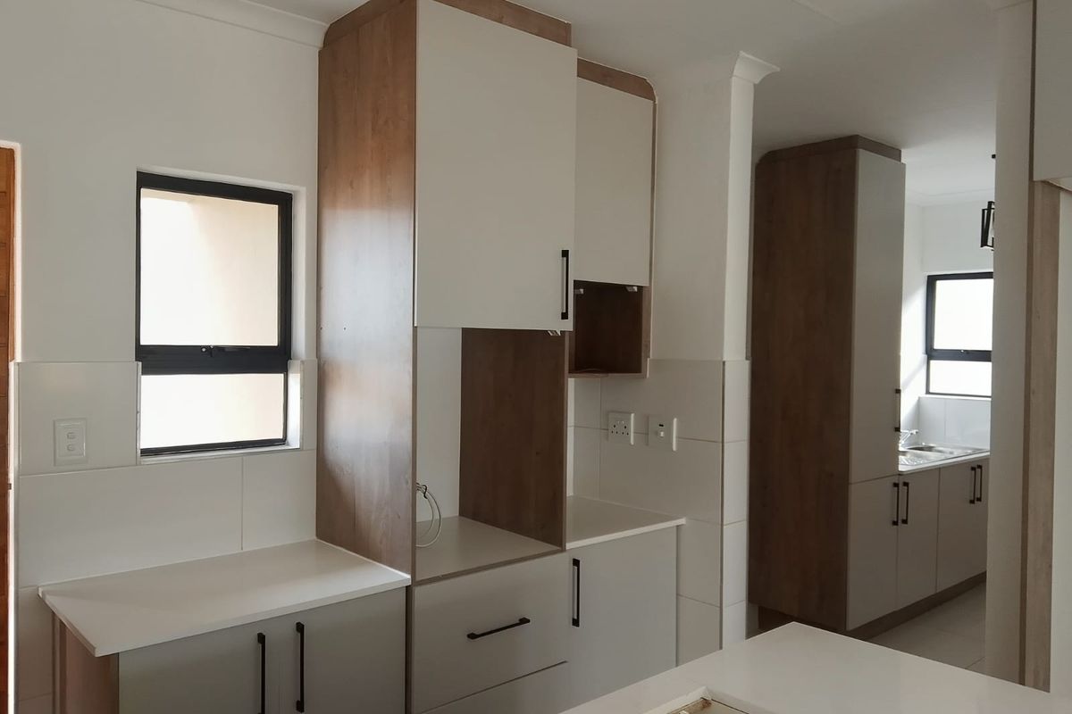 Modern kitchen featuring two-tone cabinetry, stone countertops, and tiled splashbacks, offering a clean and contemporary aesthetic with ample storage space.