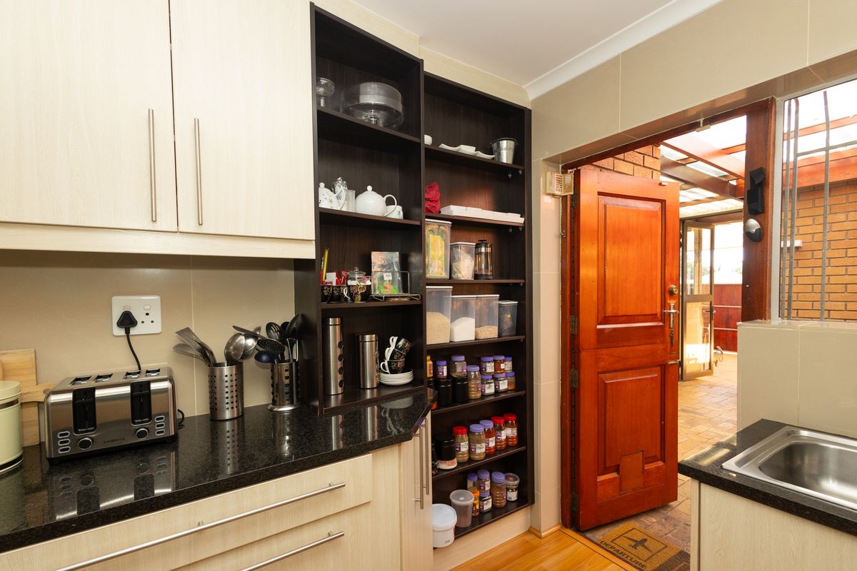 A functional kitchen area featuring dark granite countertops, light wood-toned cabinetry, and open shelving, with direct access to an outdoor patio space.
