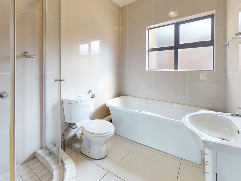 A clean, modern bathroom featuring a separate shower enclosure, bathtub, toilet, and vanity basin with neutral wall and floor tiling.
