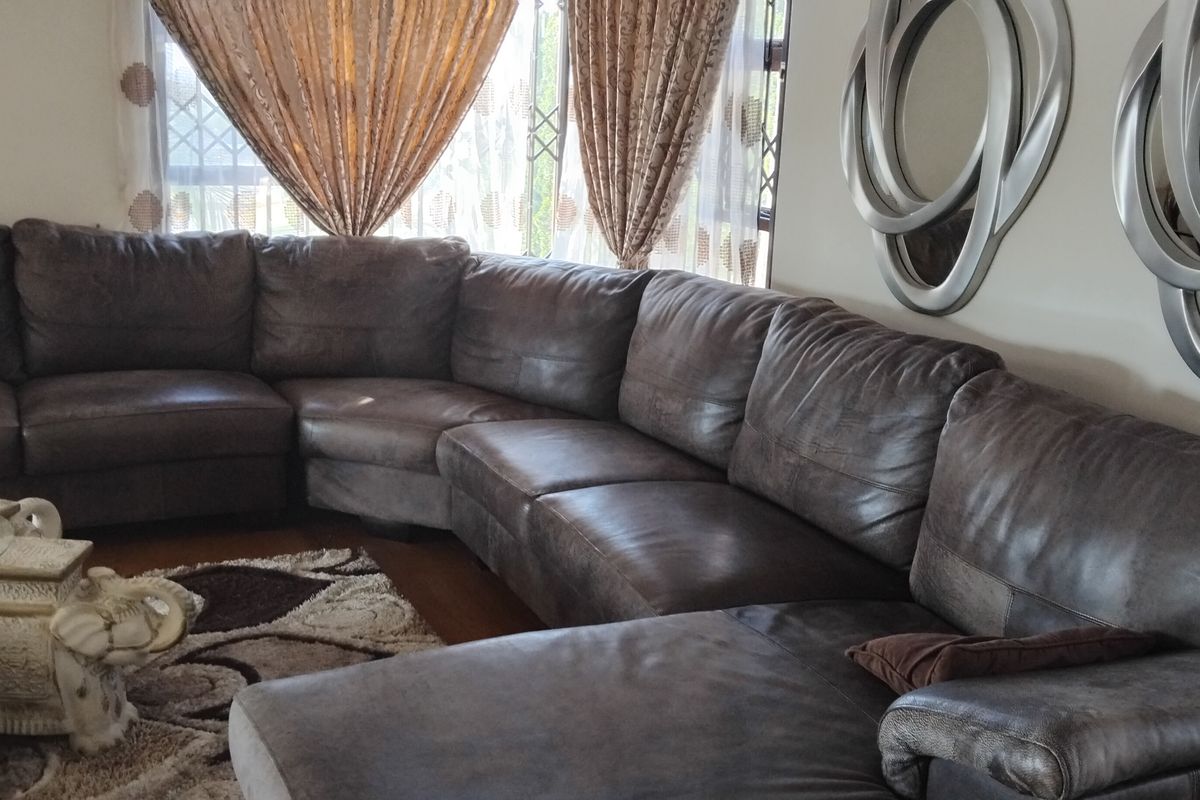 A comfortable living room area featuring large windows with security gates, providing a functional space for relaxation.