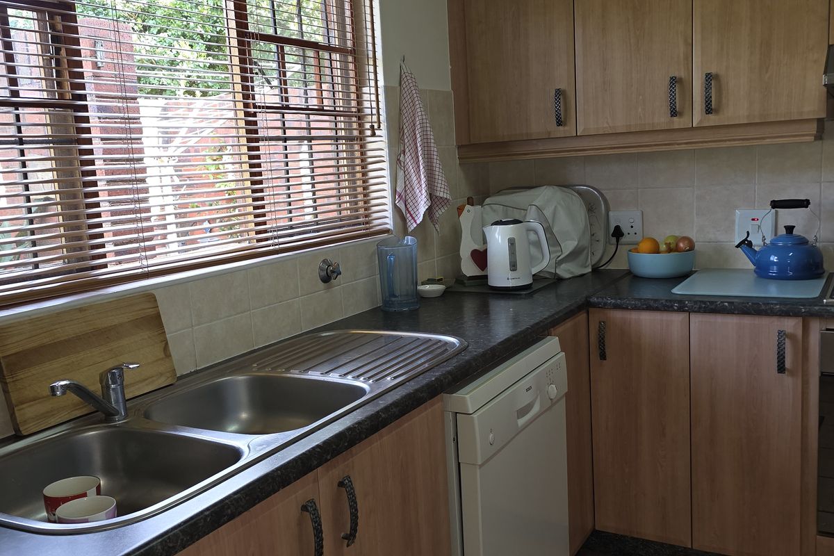 A functional kitchen featuring wood-look cabinetry, a double stainless steel sink, a built-in oven with gas hob, and an extractor fan.