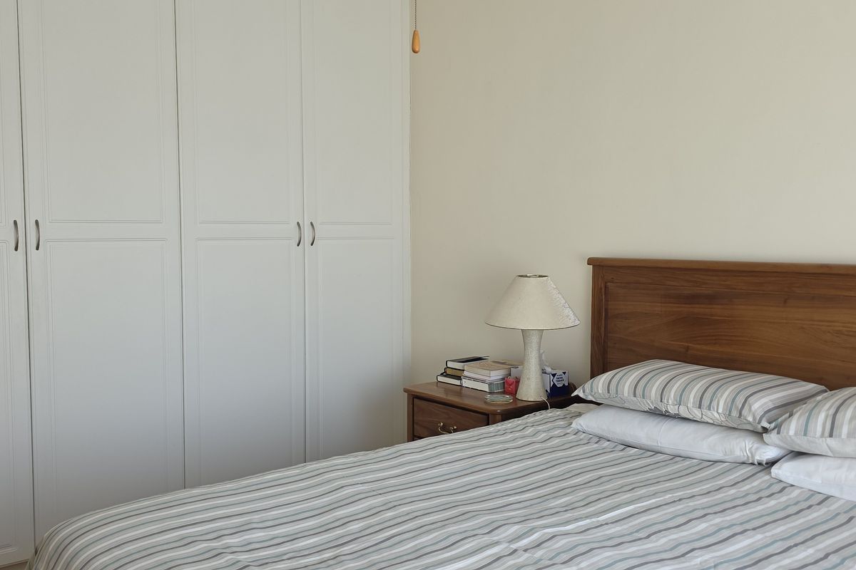 A well-maintained bedroom featuring built-in floor-to-ceiling wardrobes with classic panel detailing.