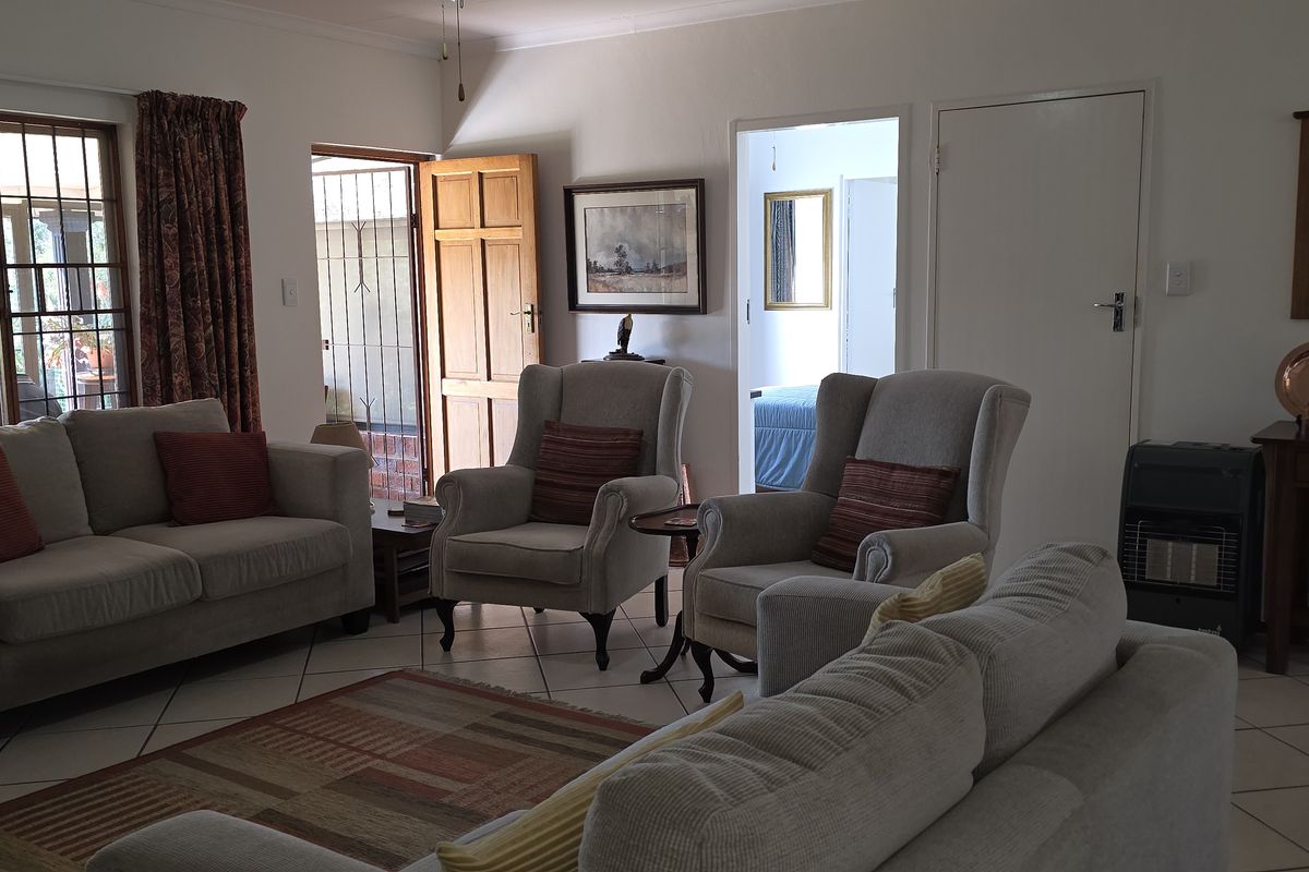 A spacious living room featuring tiled flooring, large sliding glass doors leading to an outdoor area, and access to adjacent rooms.