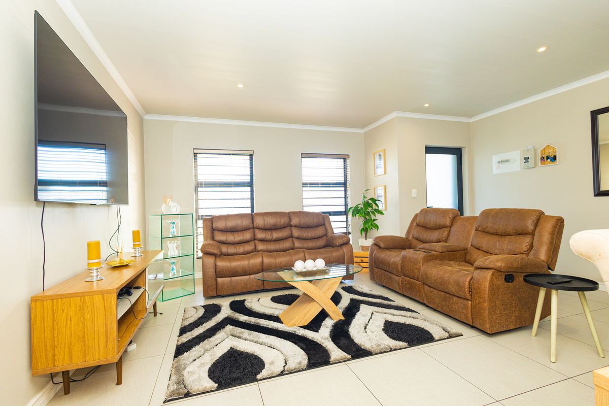 A well-maintained living room featuring neutral tiled flooring, recessed downlighting, and coved cornicing, providing a clean and functional space.
