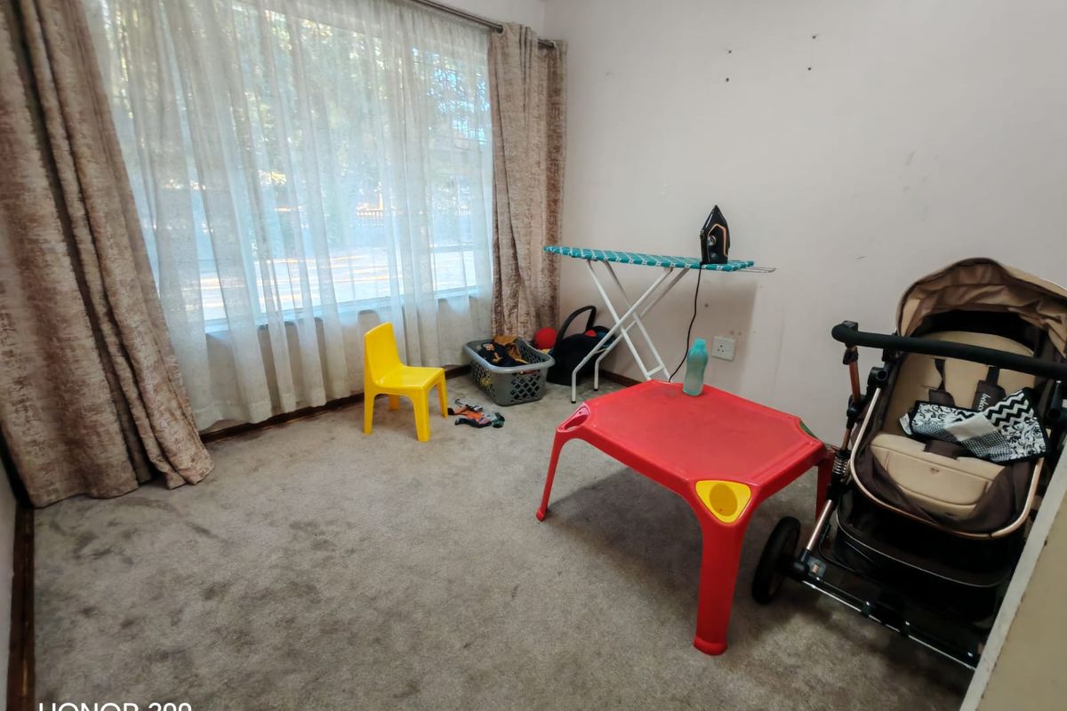 A bedroom featuring carpeted flooring and a large window with curtains, currently used as a multi-purpose space.
