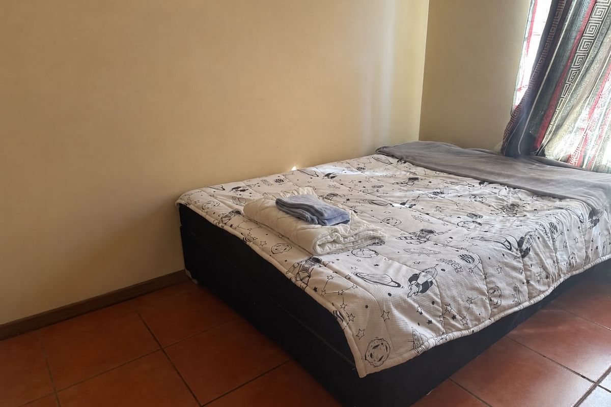 A bedroom featuring tiled flooring and natural light from the window.