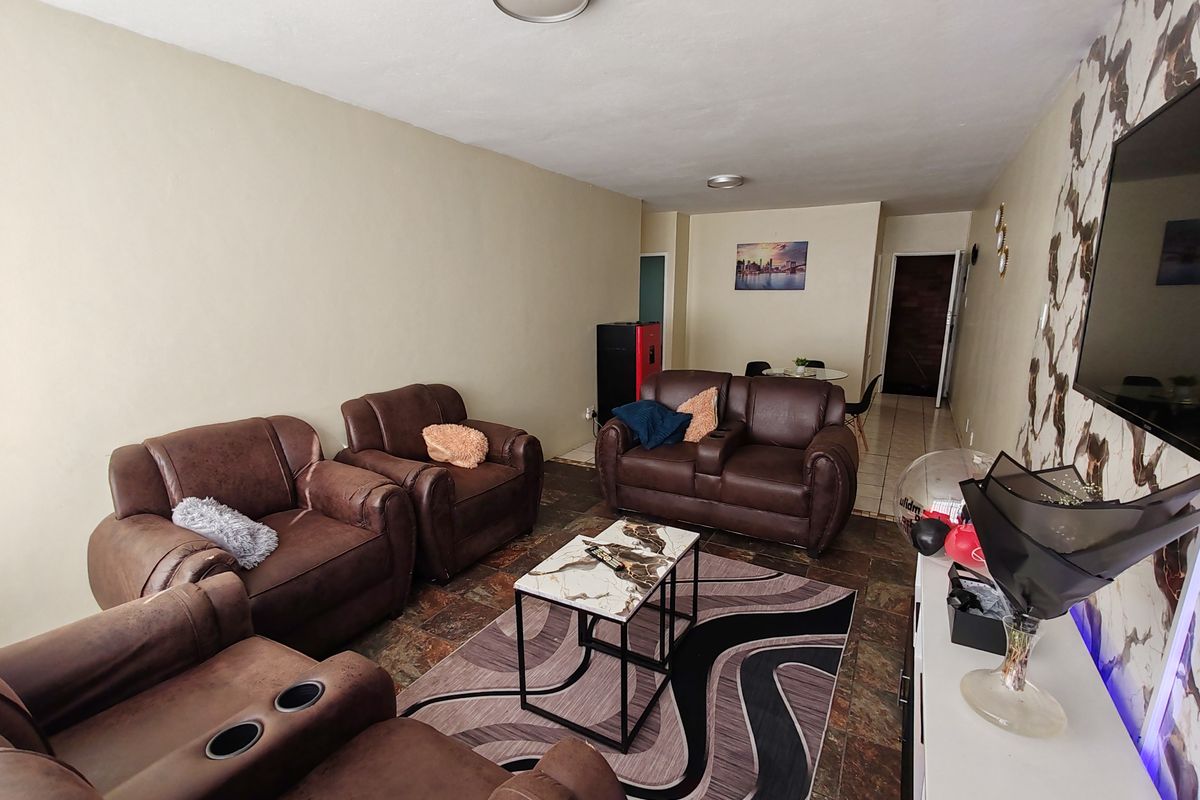 A living room area featuring tiled flooring and a feature wall, providing a functional space for relaxation and entertainment.