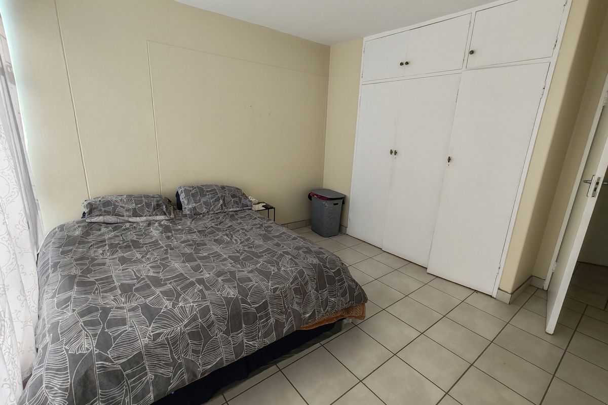 A bedroom featuring built-in storage cupboards and tiled flooring.
