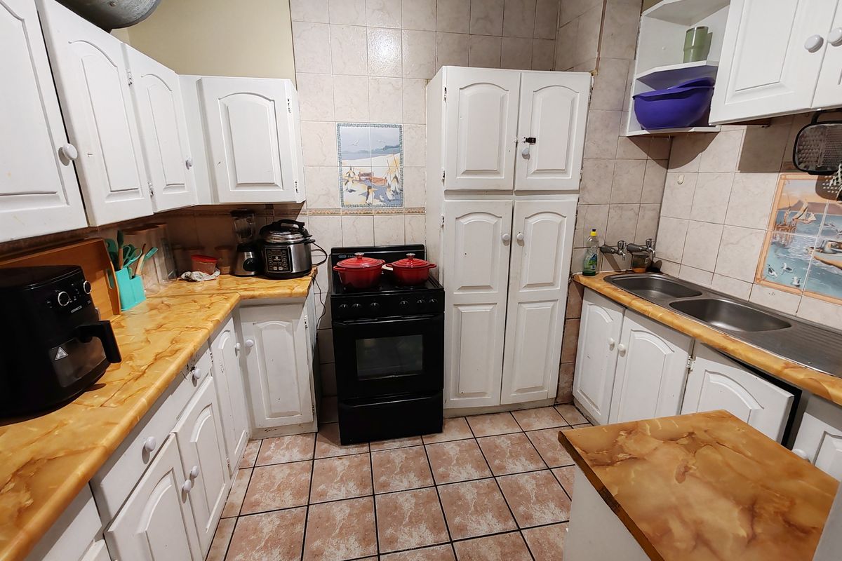 A functional kitchen featuring white cabinetry, tiled backsplash, double basin sink, and a freestanding stove, offering a practical layout for daily meal preparation.