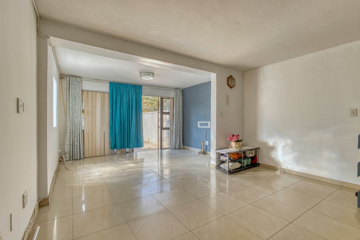 A spacious, light-filled living area featuring neutral tiled flooring and direct access to an outdoor space through a sliding glass door.