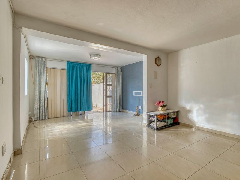 A spacious, light-filled living area featuring neutral tiled flooring and direct access to an outdoor space through a sliding glass door.