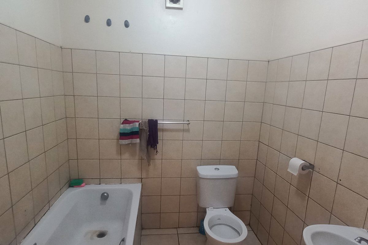 A functional bathroom featuring a standard bathtub, toilet, and basin with neutral wall tiling throughout.