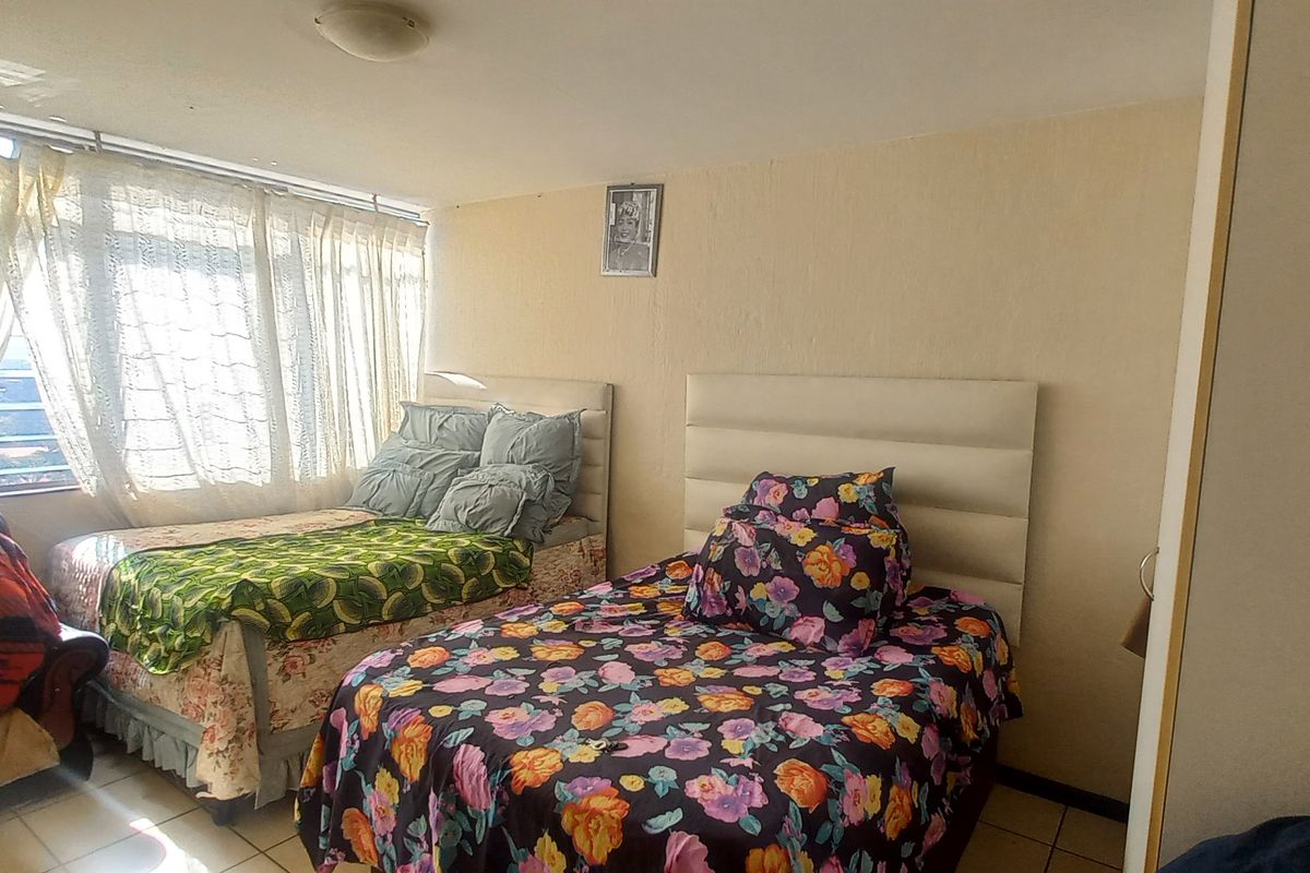 A bedroom featuring tiled flooring and large windows that provide natural light.
