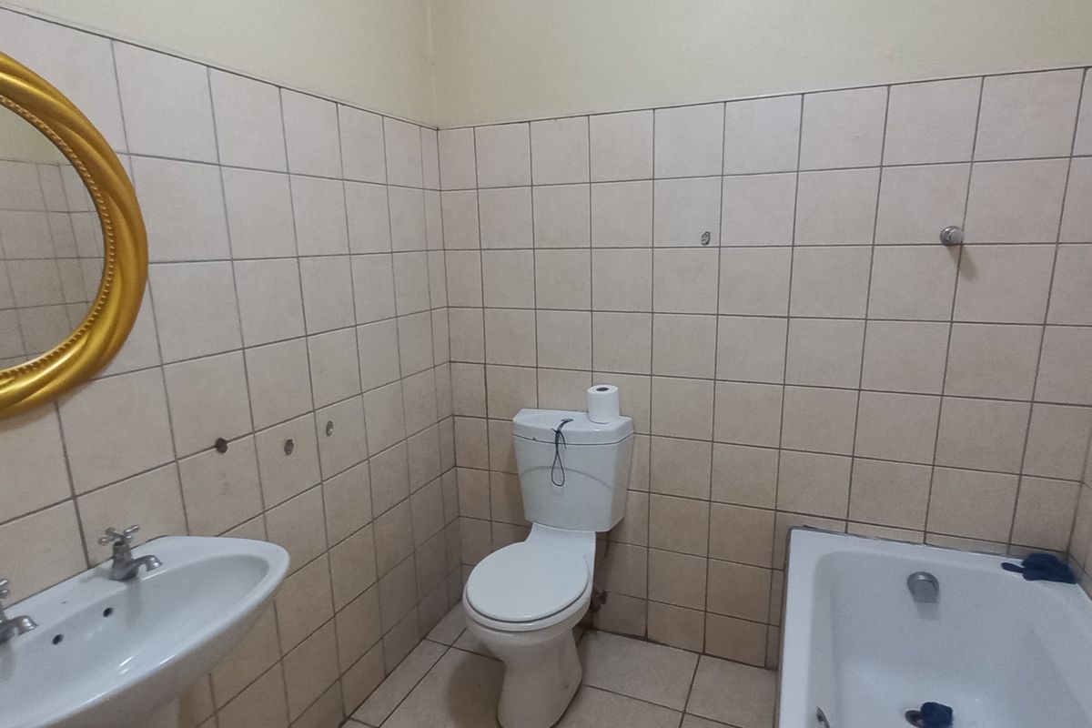 A functional bathroom featuring a pedestal basin, standard toilet, and a bathtub with full-height wall tiling.