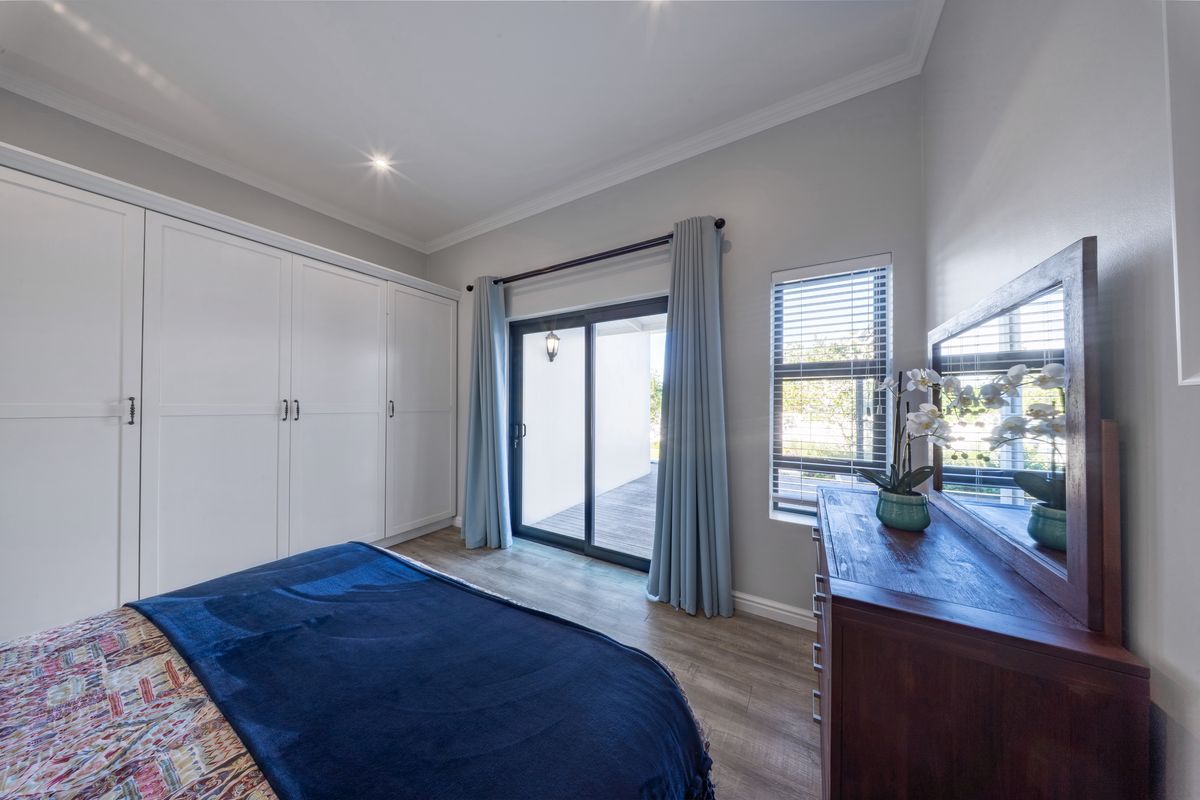 A well-maintained bedroom featuring built-in cupboards, laminate flooring, and a sliding glass door providing direct access to an outdoor patio area.