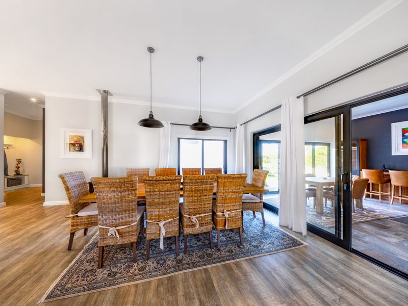 Spacious open-plan dining area featuring wood-look flooring, modern lighting, and large sliding glass doors providing seamless access to the outdoor patio.