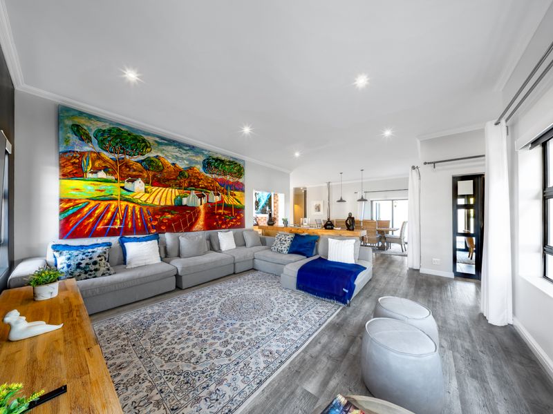 Spacious open-plan living and dining area featuring modern laminate flooring, recessed lighting, and a seamless flow between the lounge and kitchen spaces.