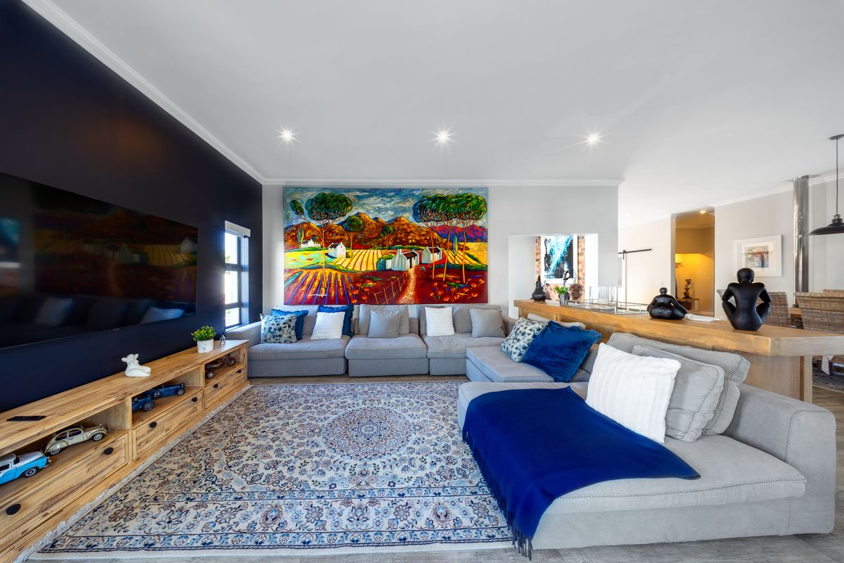 A well-maintained living room featuring a dark accent wall, recessed downlighting, and crown molding, creating a comfortable and inviting atmosphere.