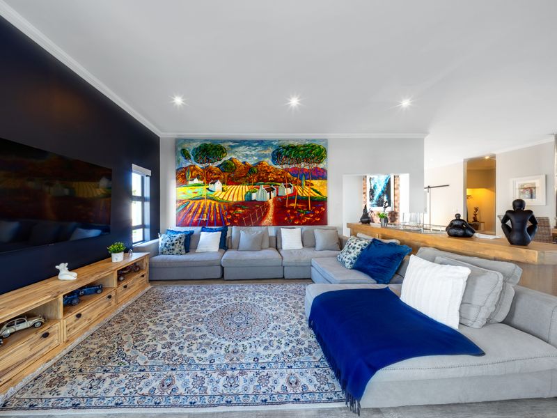 A well-maintained living room featuring a dark accent wall, recessed downlighting, and crown molding, creating a comfortable and inviting atmosphere.