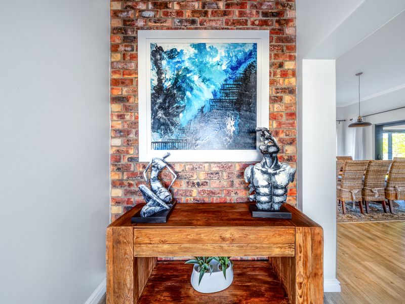 A well-maintained hallway featuring a prominent exposed brick feature wall and warm timber flooring, leading into an open-plan living area.
