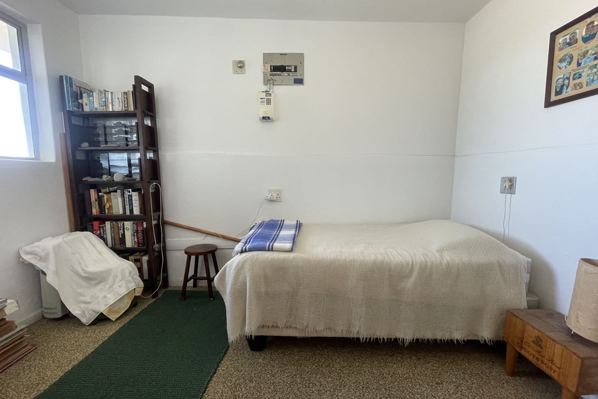 A functional bedroom featuring carpeted flooring, an integrated intercom system, and a wall-mounted electrical distribution board.