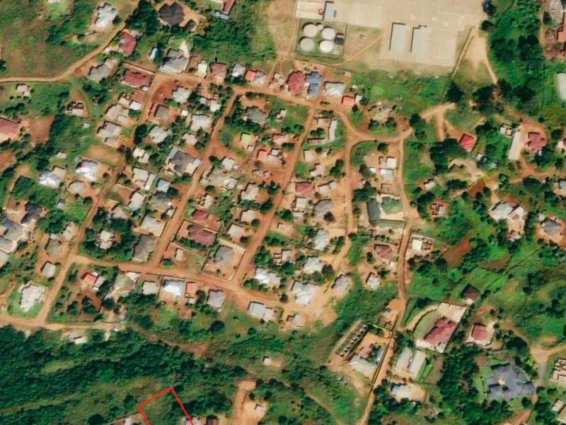 An aerial view showing a vacant residential land plot outlined in red within an established neighborhood setting.