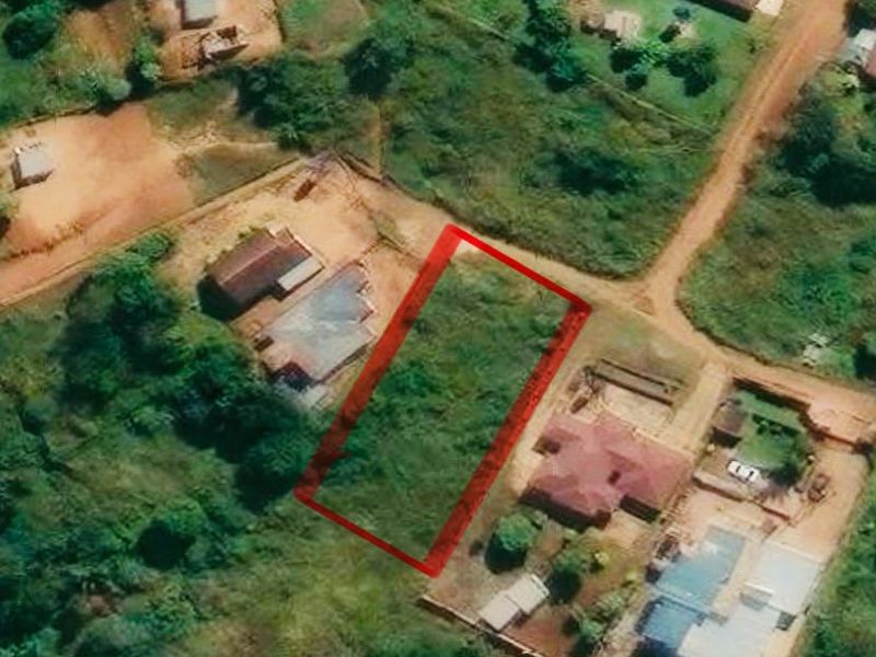 An aerial view of a vacant residential plot of land, highlighted in red, situated within an established neighborhood.