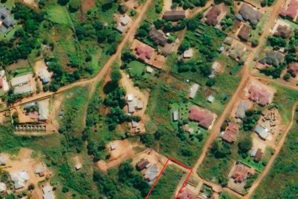 An aerial view highlighting a vacant residential land plot within an established neighborhood setting.