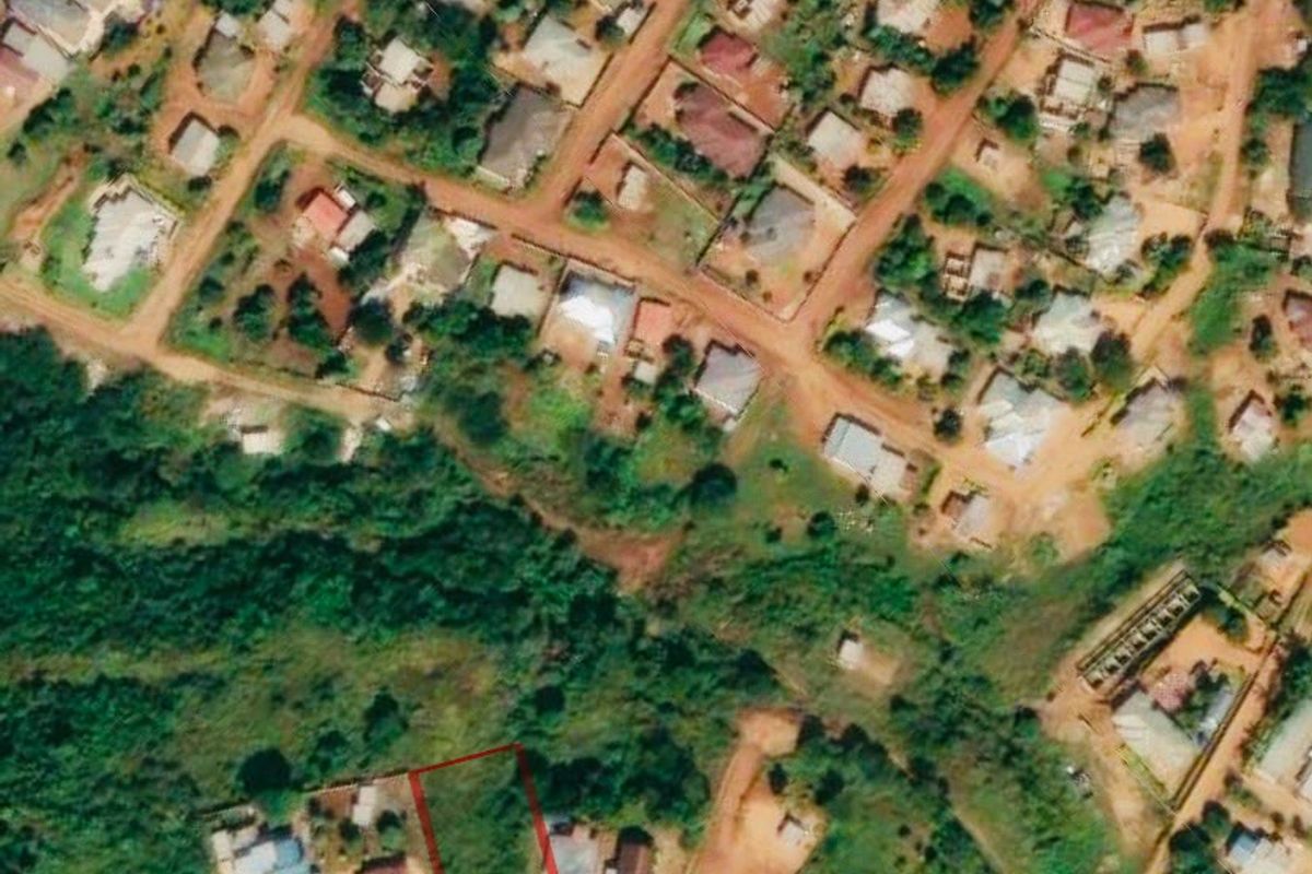 An aerial view of a residential vacant land plot highlighted in red, situated within an established neighborhood.