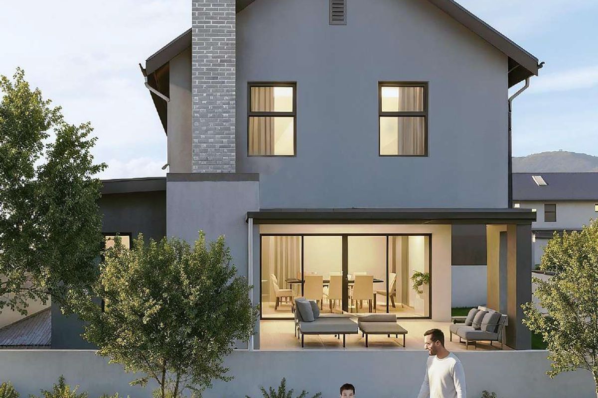 Rear view of a modern two-story house featuring a covered patio, brick chimney, and large sliding glass doors leading to the interior living space.