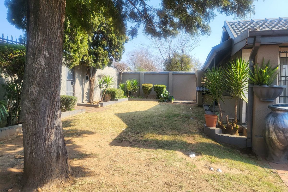 A private rear garden featuring a lawn area, perimeter boundary walls, and established trees, providing a quiet outdoor space.