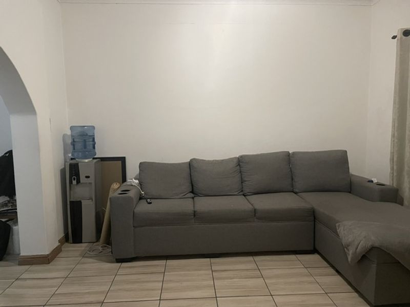 A living room area featuring neutral tiled flooring and a distinctive architectural archway leading to an adjacent space.