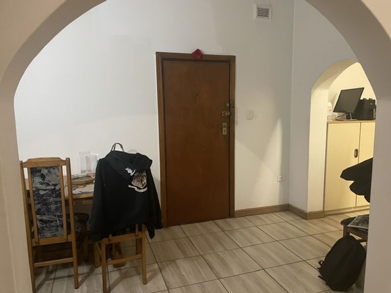 An entry area featuring tiled flooring and distinctive arched doorways leading into the living space, with a solid timber entrance door.