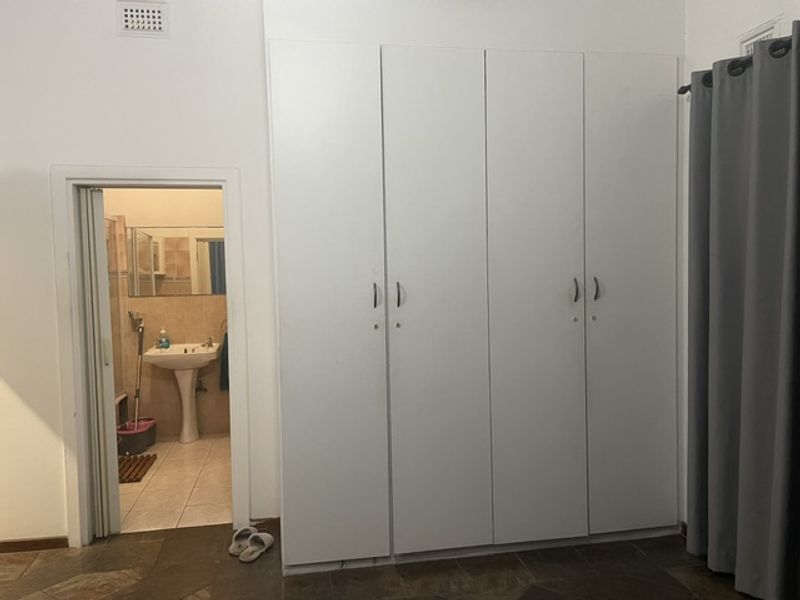 Bedroom featuring a large built-in wardrobe and direct access to an en-suite bathroom with a pedestal sink.