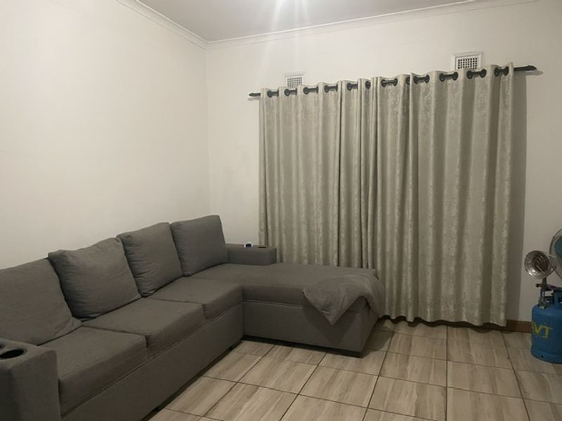 A living room featuring tiled flooring and neutral wall finishes, providing a functional space for relaxation.