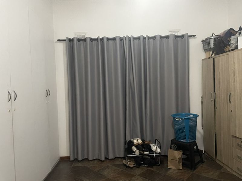 A bedroom featuring built-in wardrobes and tiled flooring, providing functional storage space.