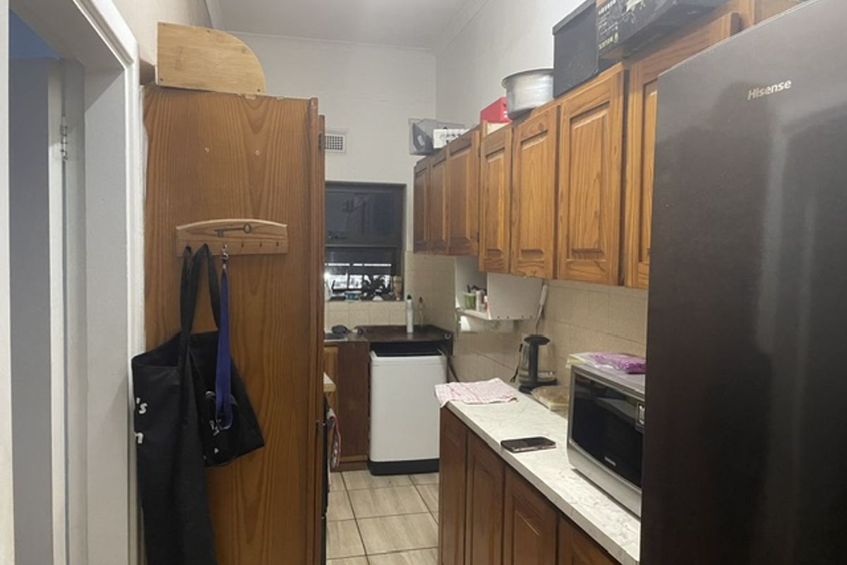 A functional kitchen featuring traditional wooden cabinetry, laminate countertops, and tiled flooring, offering potential for a modern renovation.
