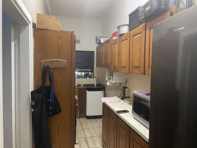 A functional kitchen featuring traditional wooden cabinetry, laminate countertops, and tiled flooring, offering potential for a modern renovation.