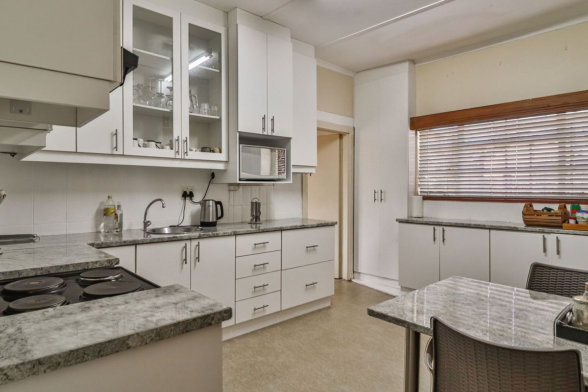 A functional kitchen featuring white cabinetry, laminate countertops, an integrated electric hob, and built-in microwave, offering a clean and practical workspace.
